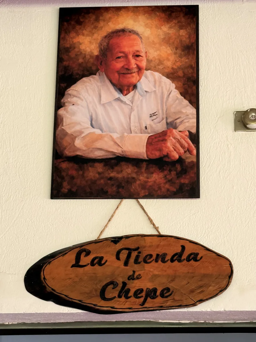 Retrato de Chepe y letrero de madera del salón La Tienda de Chepe